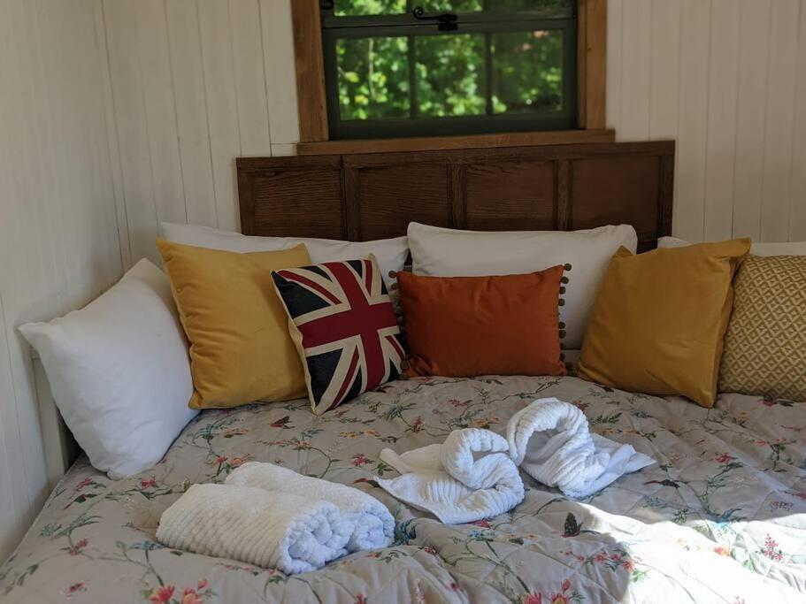 Una cama con toallas y almohadas encima. en Kenny’s Hut en Cowfold