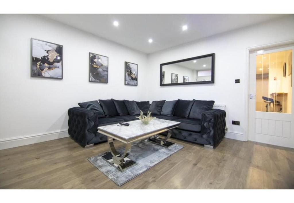 a living room with a black couch and a table at Stunning Bolton abode – Pool table – Parking in Bolton