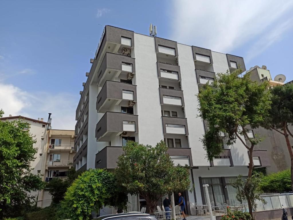 a tall white building with trees in front of it at Dias Hotel in Kusadası