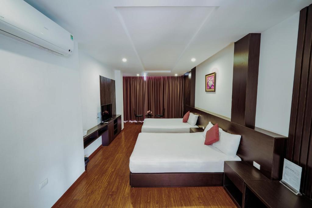 a hotel room with two beds and a tv at Ivy Hotel in Ha Long