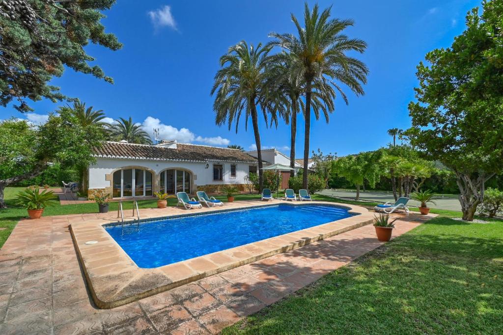 a swimming pool in front of a house with palm trees at Villa Nathalie in Jávea