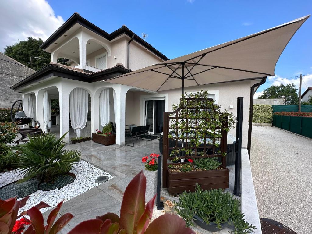 una casa blanca con un paraguas en un patio en Villa Zonta Apartment Maremi with private jacuzzi, en Buje
