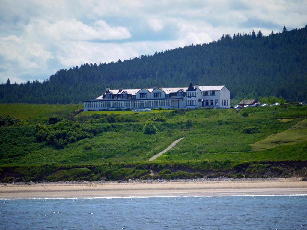 a large house on top of a hill next to the ocean at Cullen Bay Hotel in Cullen