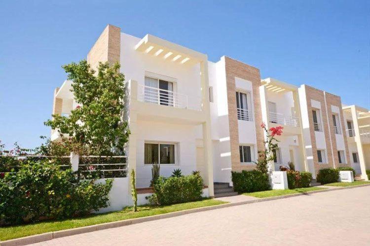 a large white house with a street in front of it at Sidi Rahal Villa avec piscine à 5min de la plage in Dar Hamida