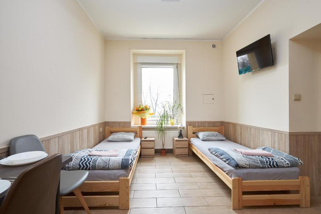 Cette chambre comprend 2 lits, une table et une fenêtre. dans l'établissement Apartamenty P7 Dzierżoniów, à Dzierżoniów