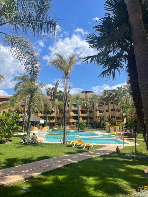 een zwembad met palmbomen en een resort bij Costalita Playa in Estepona