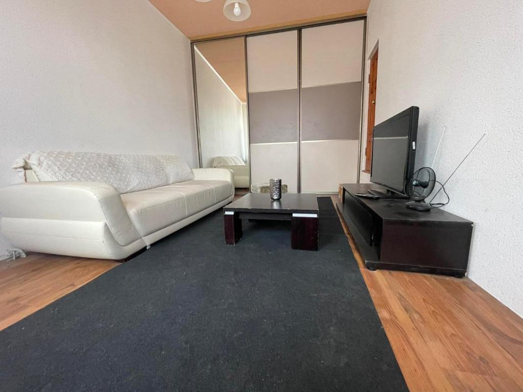 a living room with a white couch and a tv at Apartment in Kaunas center in Kaunas