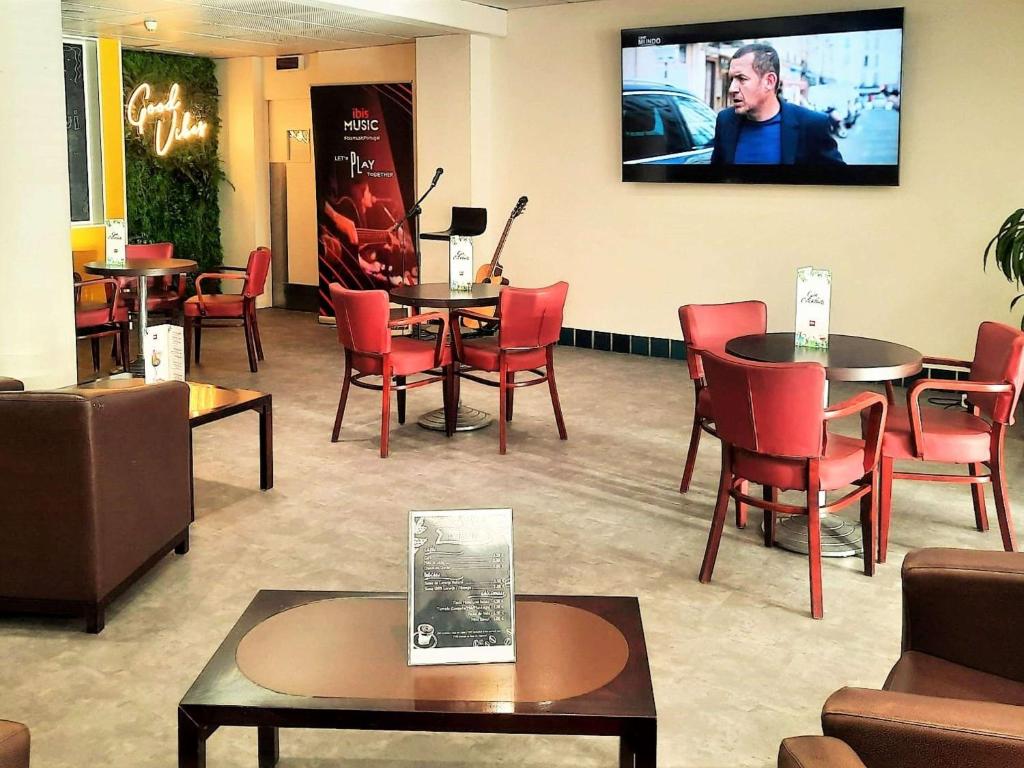 una sala d'attesa con tavoli, sedie e TV a schermo piatto di Hotel ibis Porto Sul Europarque a Santa Maria Da Feira