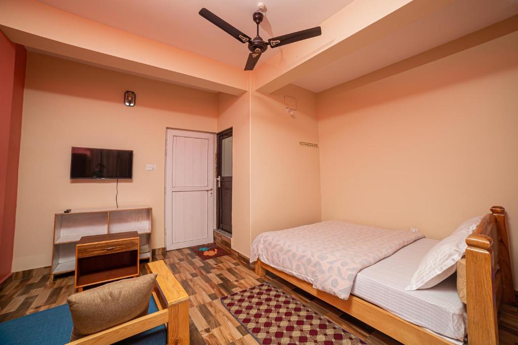 Schlafzimmer mit einem Bett, einem Schreibtisch und einem Deckenventilator in der Unterkunft Subedi Apartment in Pokhara
