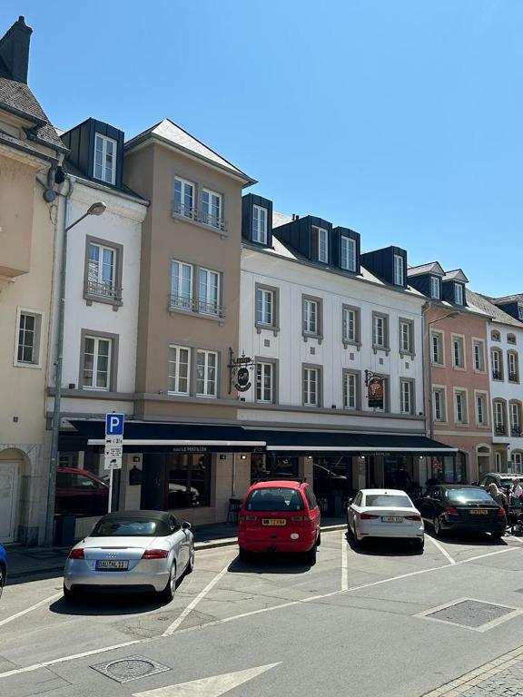 a parking lot with cars parked in front of a building at Hotel Le Postillon in Echternach