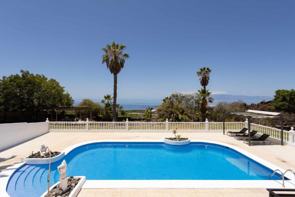 una piscina con una valla blanca y palmeras en Villa Las Flores, en Acantilado de los Gigantes