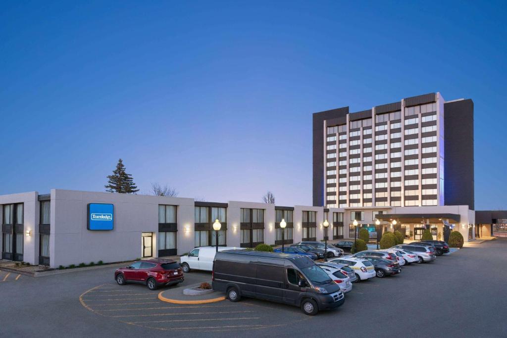 un estacionamiento con autos estacionados frente a un edificio en Travelodge by Wyndham Quebec City Hotel & Convention Centre, en Quebec