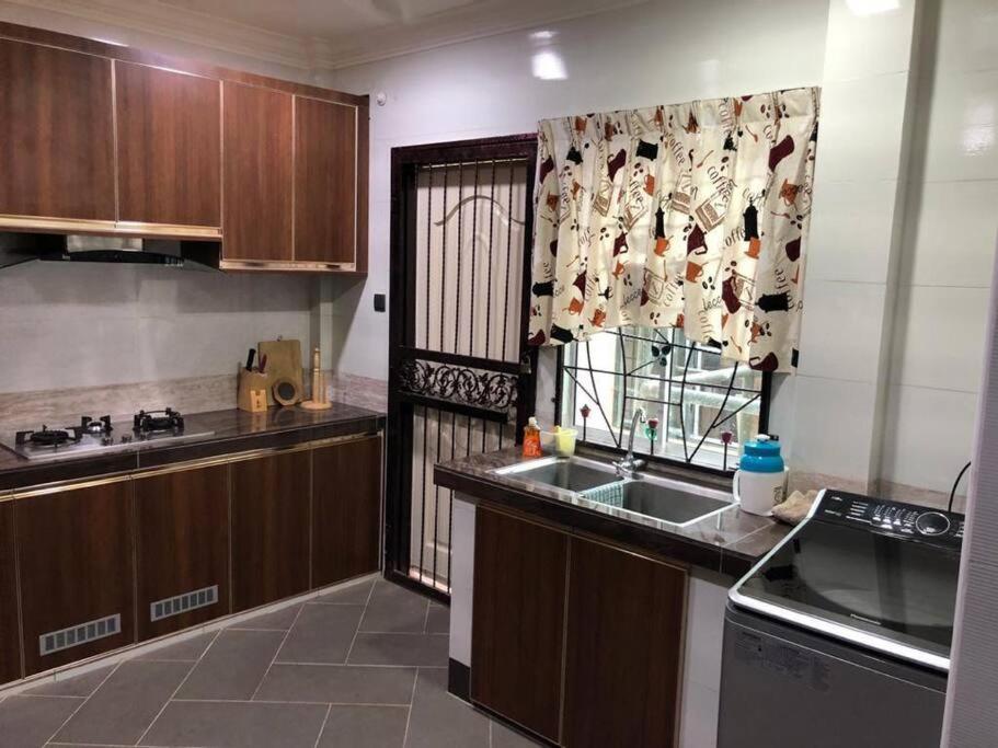 a kitchen with wooden cabinets and a sink and a window at Ceria Homestay Putatan in Putatan