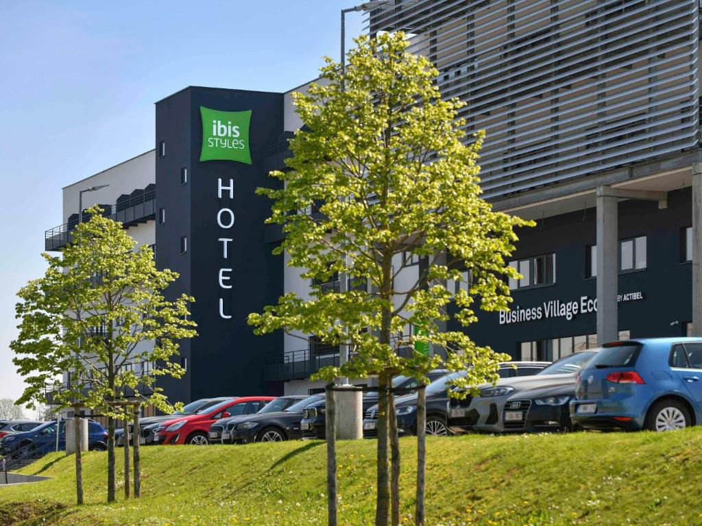 een gebouw met auto's geparkeerd op een parkeerplaats bij ibis Styles Namur in Namen