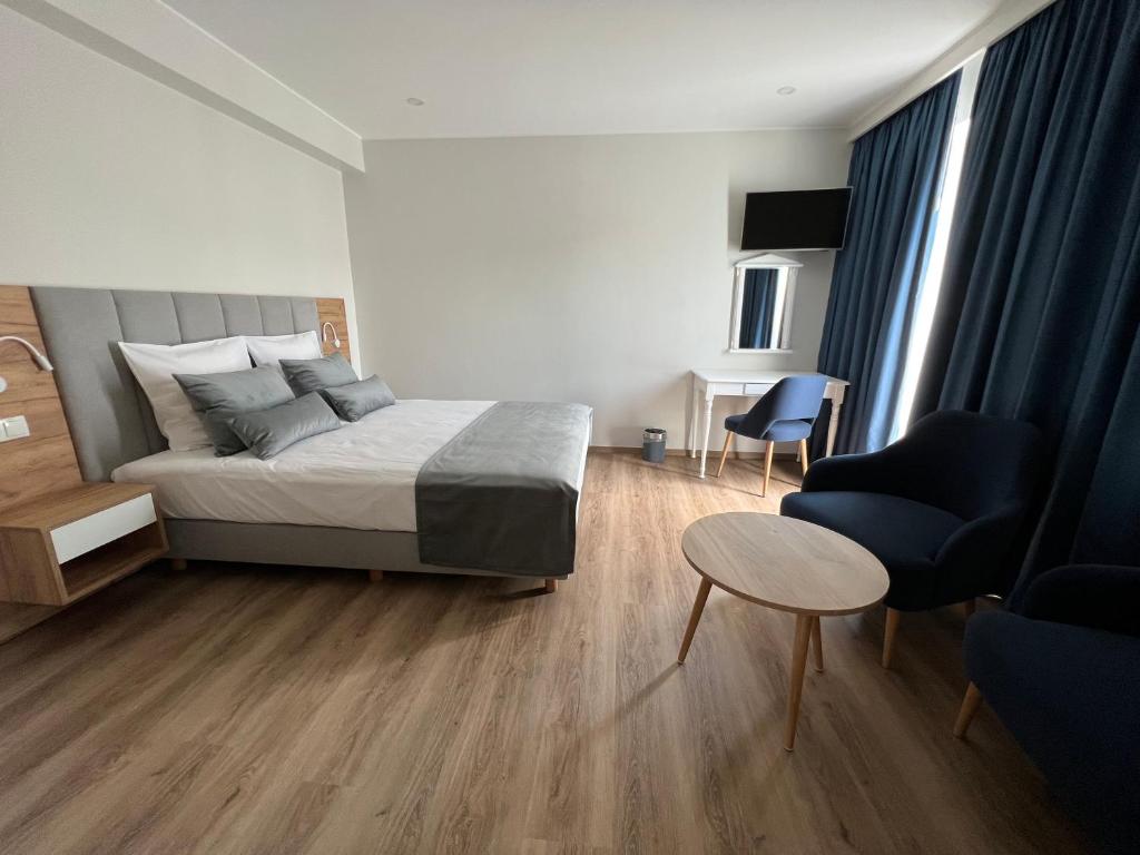 a bedroom with a bed and a table and chairs at Hotel Le Postillon in Echternach