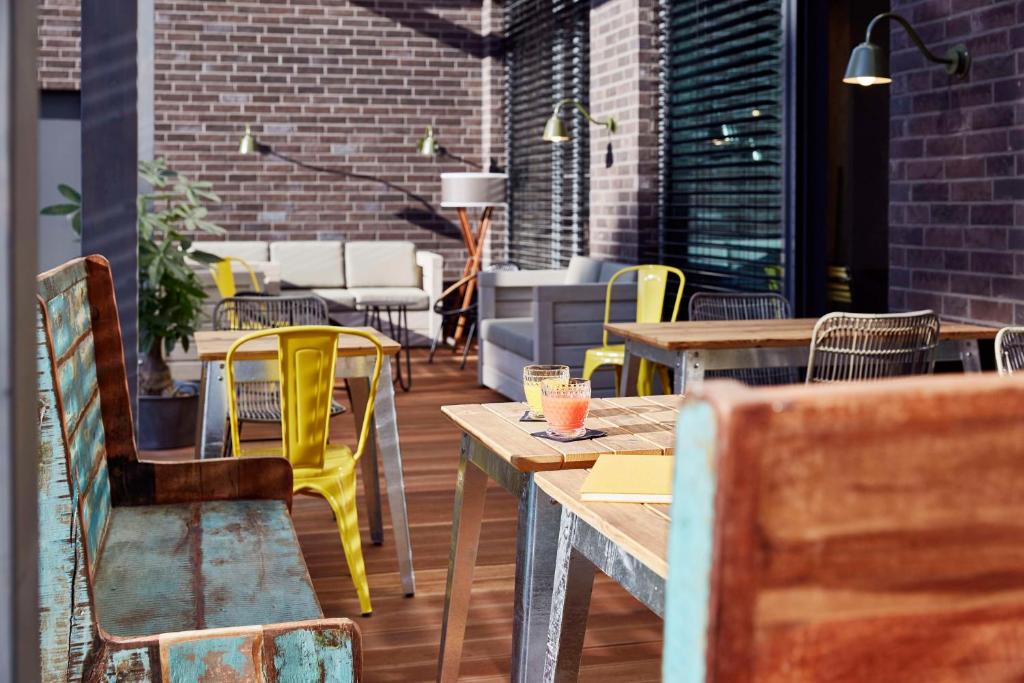 a restaurant with wooden tables and yellow chairs at me and all hotel Mainz, part of JdV by Hyatt in Mainz