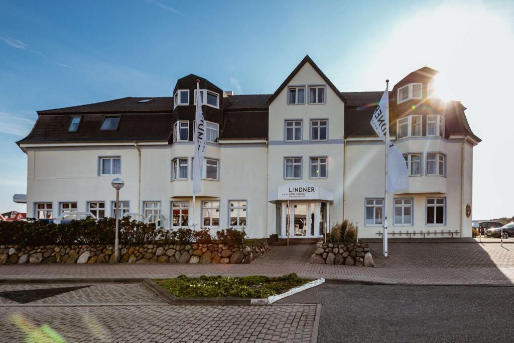 un grand bâtiment blanc avec drapeaux devant lui dans l'établissement Lindner Hotel Sylt, à Wenningstedt