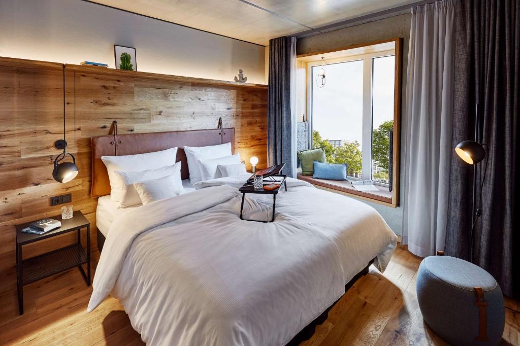 - une chambre avec un grand lit blanc et une fenêtre dans l'établissement me and all hotel Kiel, part of JdV by Hyatt, à Kiel