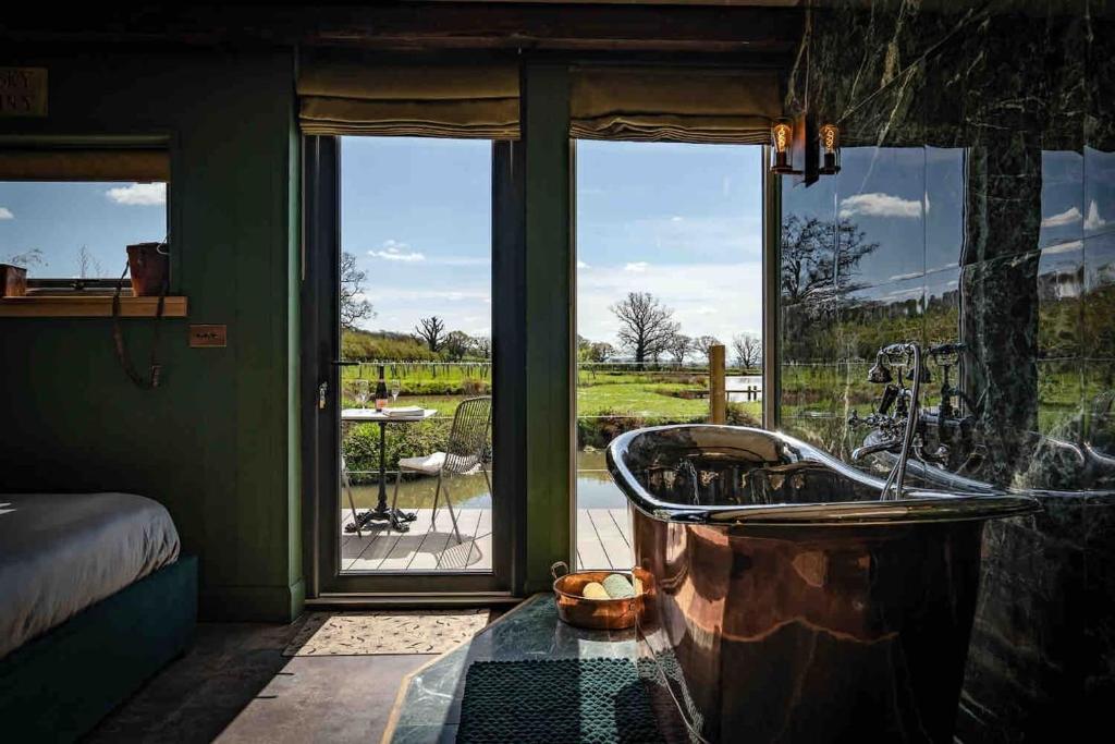 uma banheira num quarto com uma grande janela em Waters edge em Cucklington