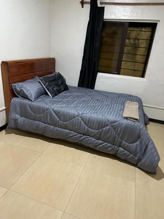 a bed with a blue comforter in a bedroom at Axe Apartments in Solwezi