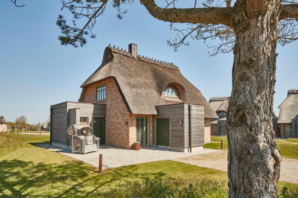 an old house with a thatched roof and a fireplace at Reetdorf Geltinger Birk Künstlerkate Sandkoppel in Nieby