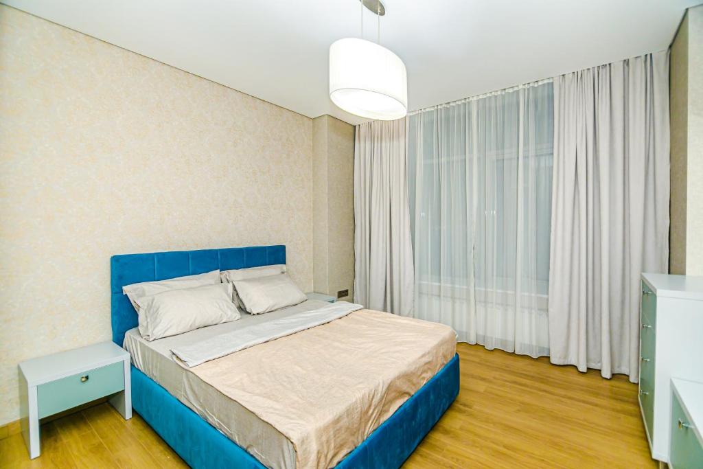 um quarto com uma cama azul e uma janela em Baku İn Front of Ritz Carlton hotel apartment em Baku