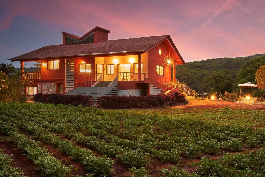 a large house with a field in front of it at StayVista's Amoda Villa - Near Venna Lake, Amidst Farmland with Jacuzzi and Indoor Activities in Mahabaleshwar