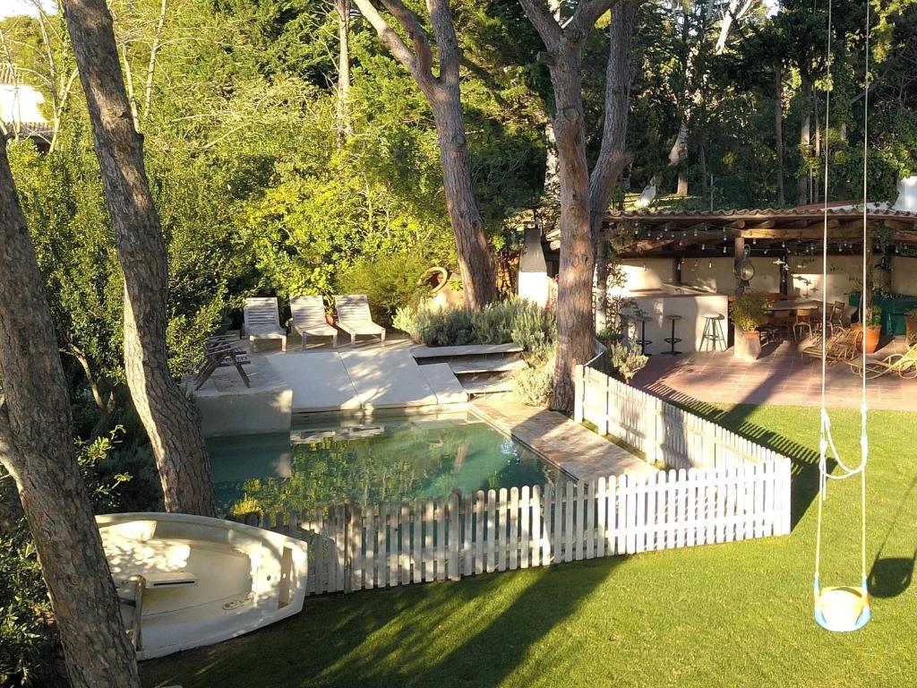 a backyard with a pool with a swing and trees at VILLA CANADELL - great garden, 5 min to beach in Palafrugell