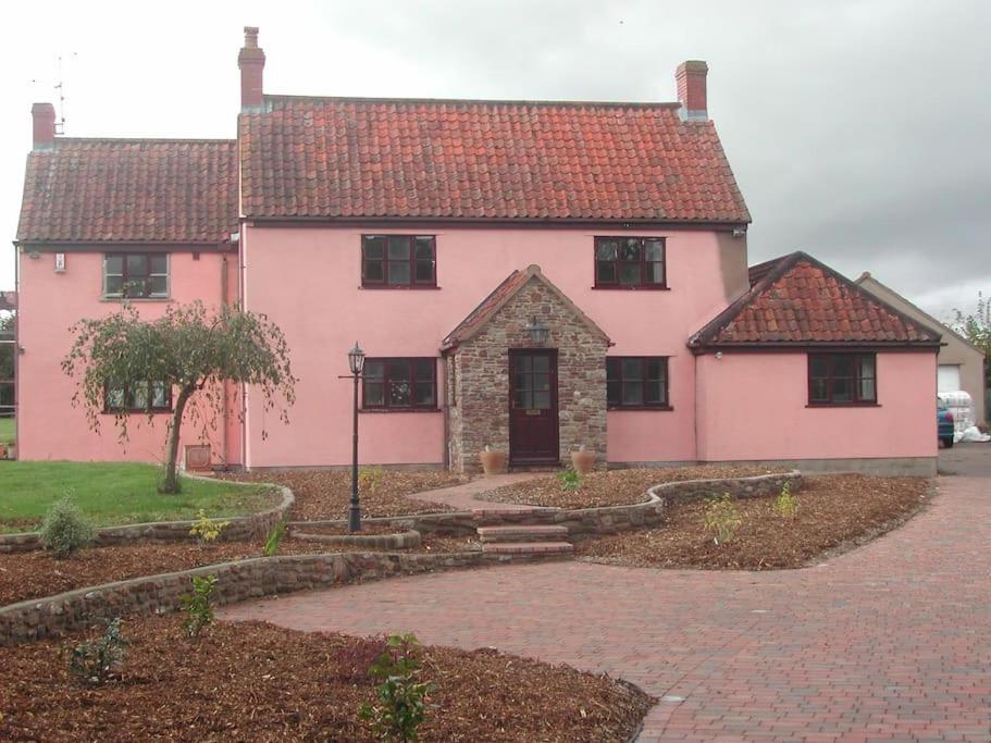 una casa rosa con techo rojo en A nicely presented friendly comfortable cottage, en Thornbury