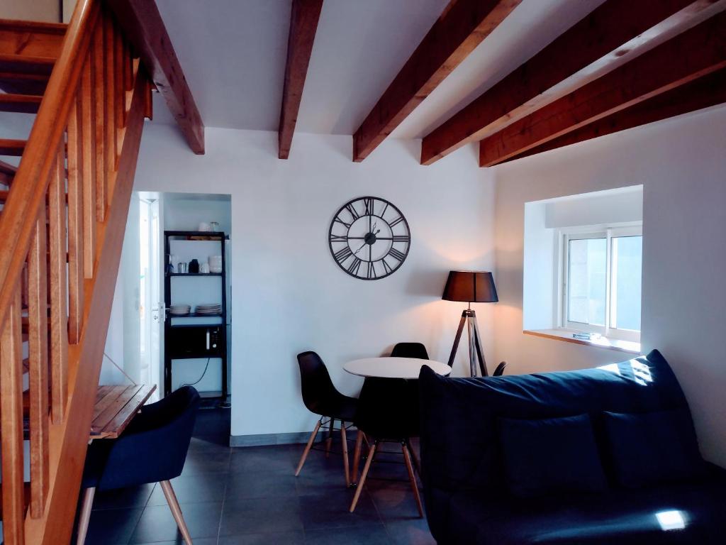 ein Wohnzimmer mit einem Tisch und einer Uhr an der Wand in der Unterkunft Le Duplex, parking wifi aux portes de vannes in Vannes