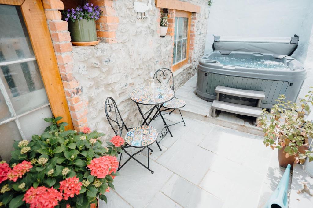 a patio with a table and chairs and flowers at Quaint cosy cottage with a hot tub in Tenby centre in Pembrokeshire