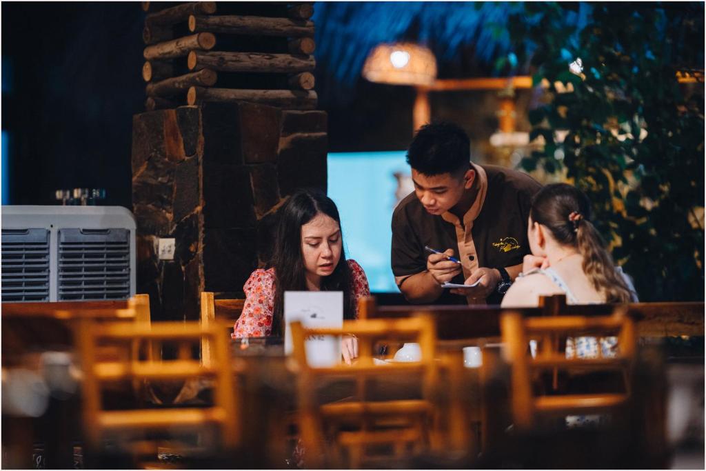 two people sitting at a table looking at a cell phone at Trang An Ecolodge in Ninh Binh
