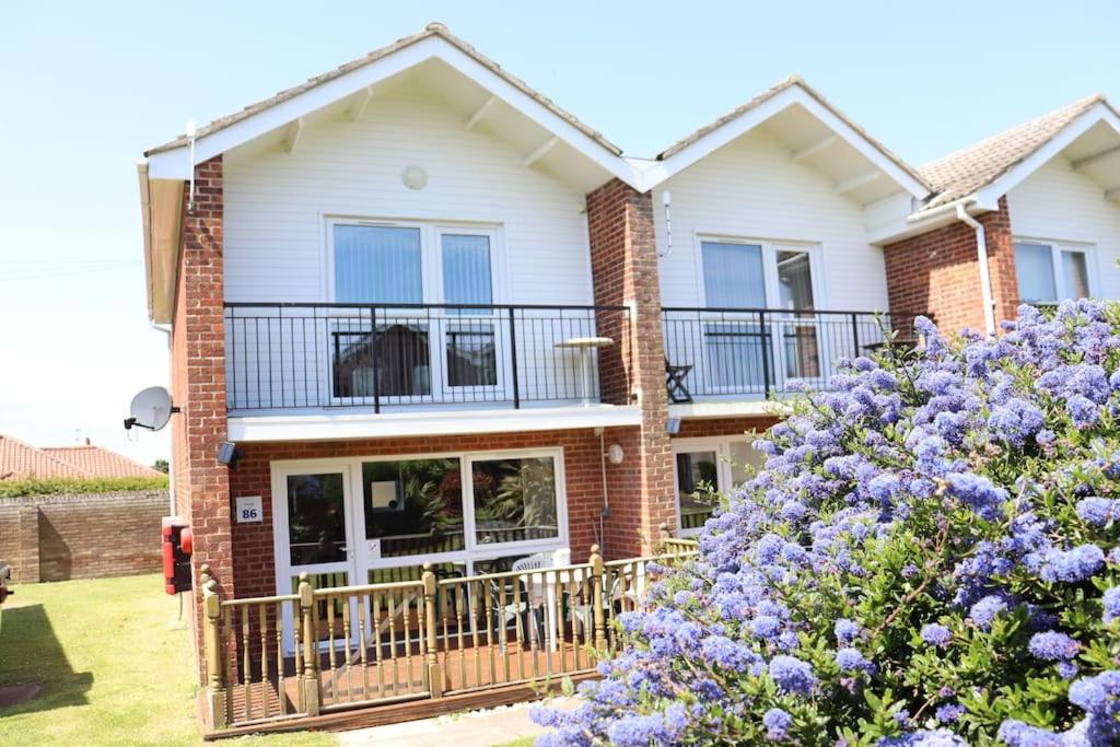 a house with a balcony and purple flowers at Corton Retreats At Waterside Park in Corton