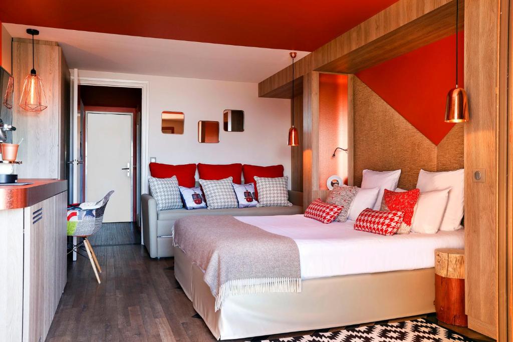 a bedroom with a large bed with red and white pillows at Grandes Rousses Hotel & Spa in L'Alpe-d'Huez