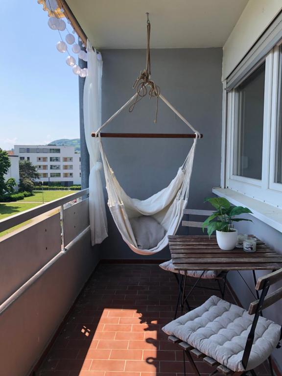 a hammock on a balcony with a table and a window at Ferienwohnung am Grütt in Lörrach