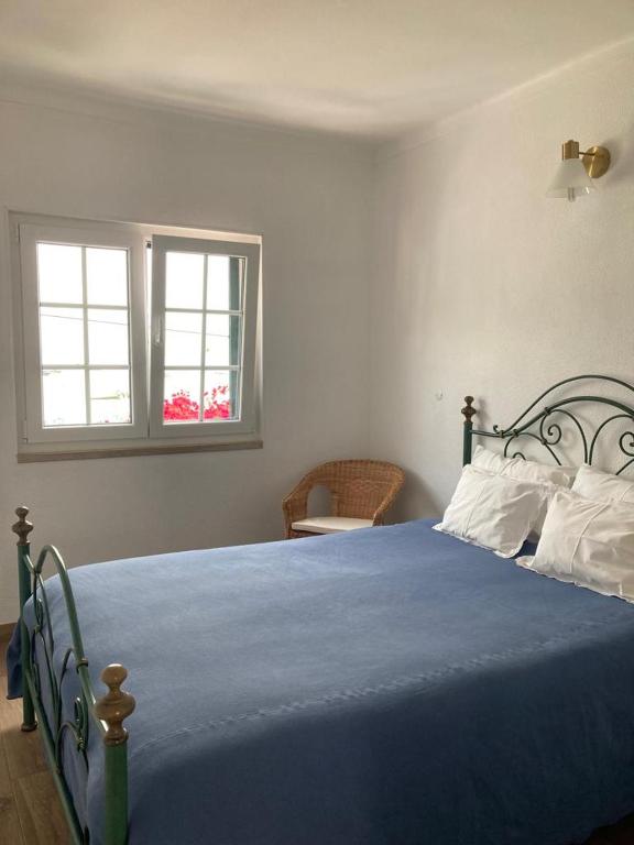 a bedroom with a blue bed with a window at Casa da Nazaré in Portinho da Arrábida