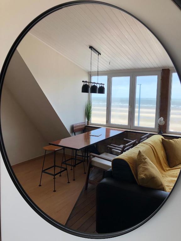 un miroir reflétant un salon avec une table et des chaises dans l'établissement Villaloha, à Bray-Dunes