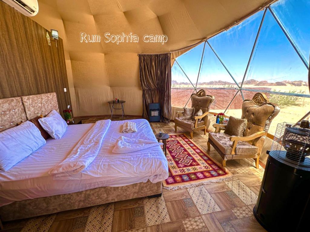 een slaapkamer in een tent met een bed en 2 stoelen bij Rum Sophia camp in Wadi Rum