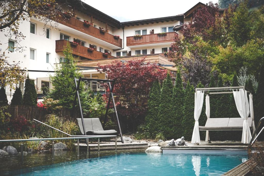 a swimming pool with two chairs and a swing at Wiesenhof Gardenresort in San Leonardo in Passiria