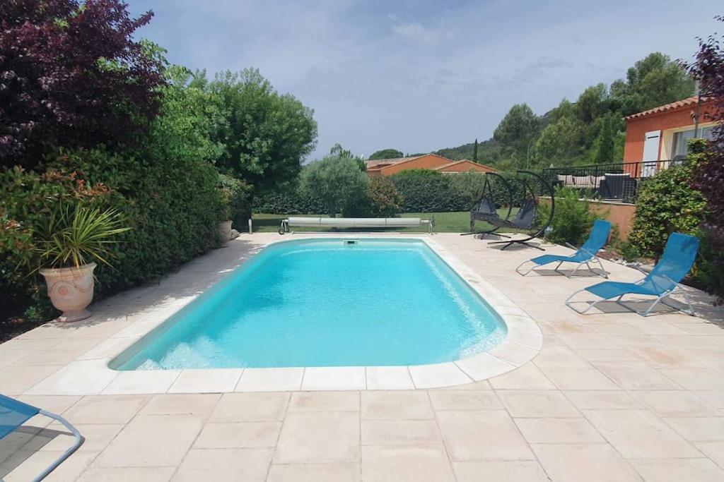 a swimming pool with two chairs and a table at Maison en Provence verte entre mer et lacs in Camps-la-Source