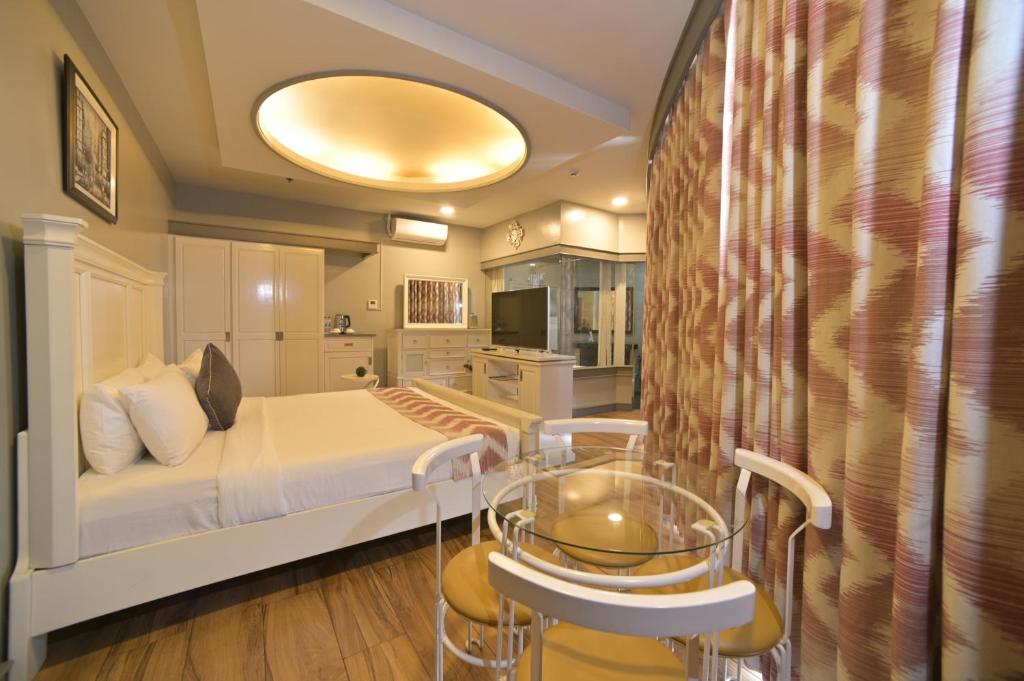 1 dormitorio con 1 cama, mesa y sillas en Paragon Hotel and Suites en Baguio