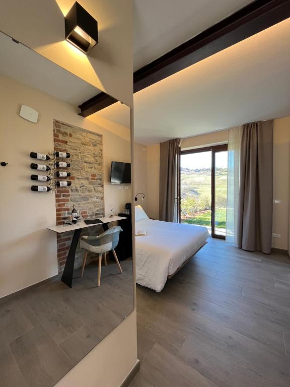 a hotel room with a bed and a desk and a bedroom at Le Cornici - Cascina di Charme in Diano dʼAlba