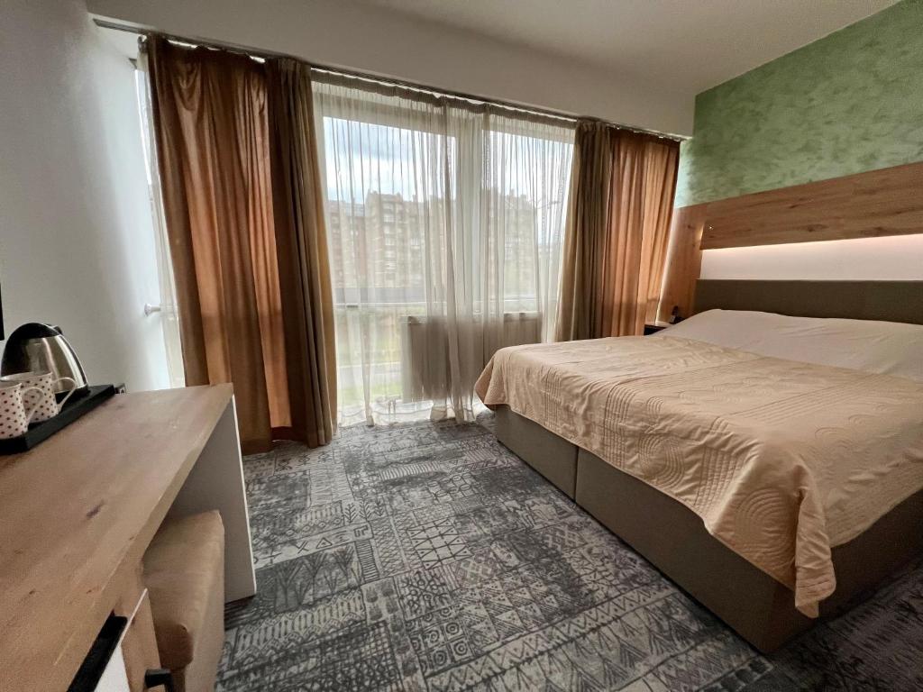 ein Hotelzimmer mit einem Bett und einem großen Fenster in der Unterkunft Hotel Brkic in Sarajevo