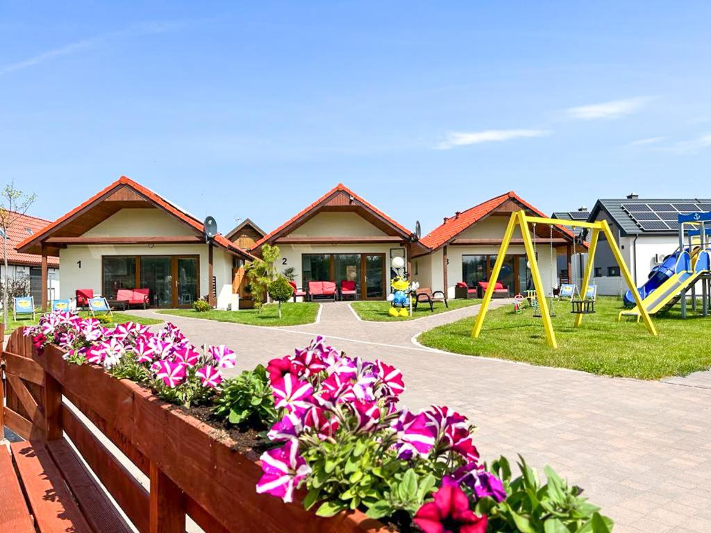 una valla con flores y un parque infantil frente a una casa en OKej domki Łeba - Nowęcin, en Nowecin