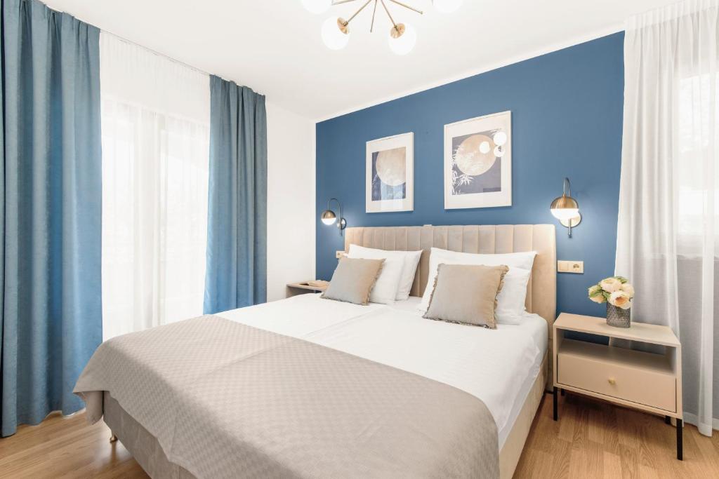 1 dormitorio con 1 cama grande y paredes azules en Apartments Villa Ana, en Poreč