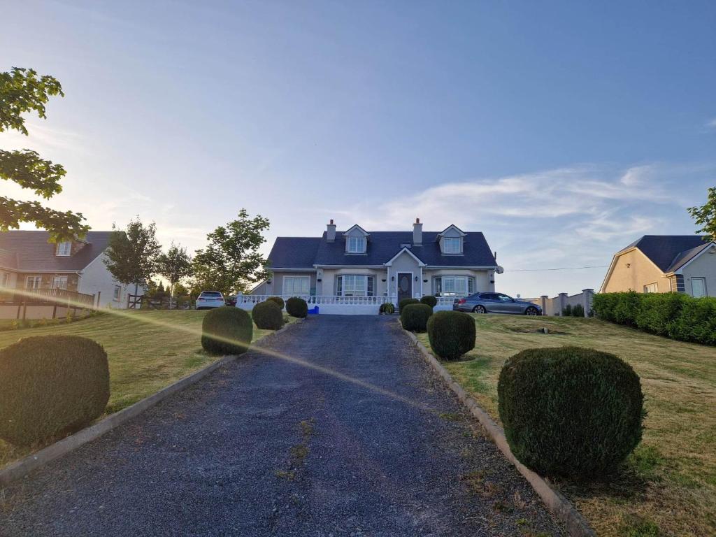 a white house with a blue roof and a driveway at Forest View Dunmore Galway H54P897 in Dunmore