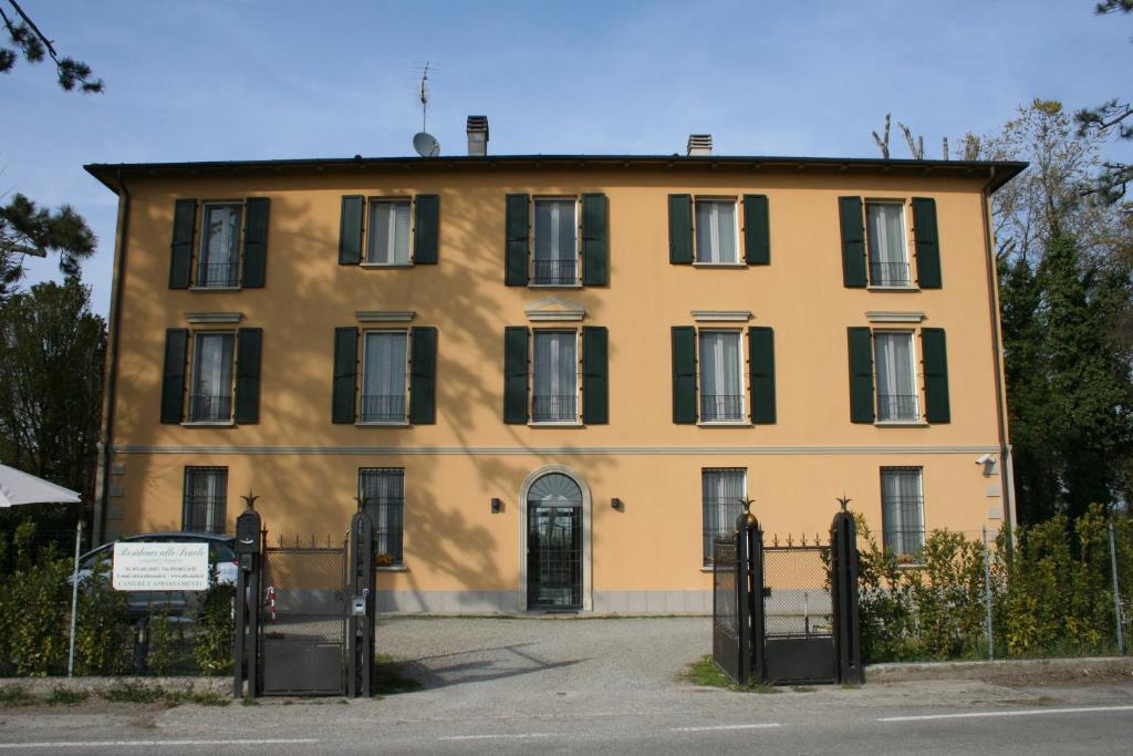 a large yellow house with black windows and a fence at Residence Alle Scuole Country House in Granarolo dellʼEmilia