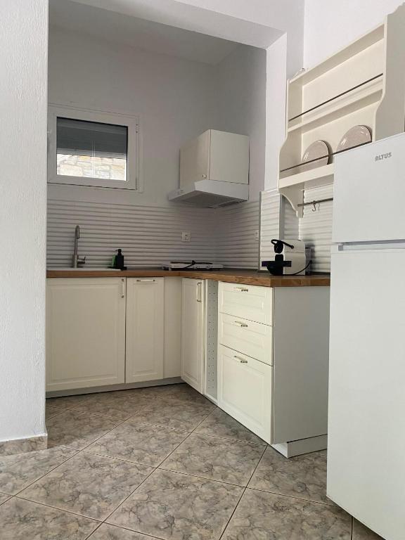 a kitchen with white cabinets and a white refrigerator at Petra Mare Apartments in Alyki