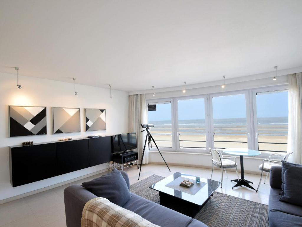een woonkamer met een bank en een tv bij Cockpit 0102 apartment overlooking the sea in De Haan