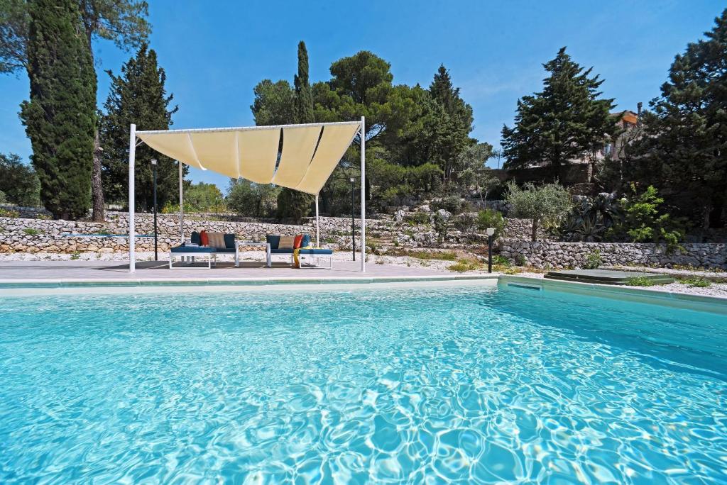 una gran piscina con una sombrilla bronceada. en Villa Pica by PosarelliVillas, en San Corrado di Fuori